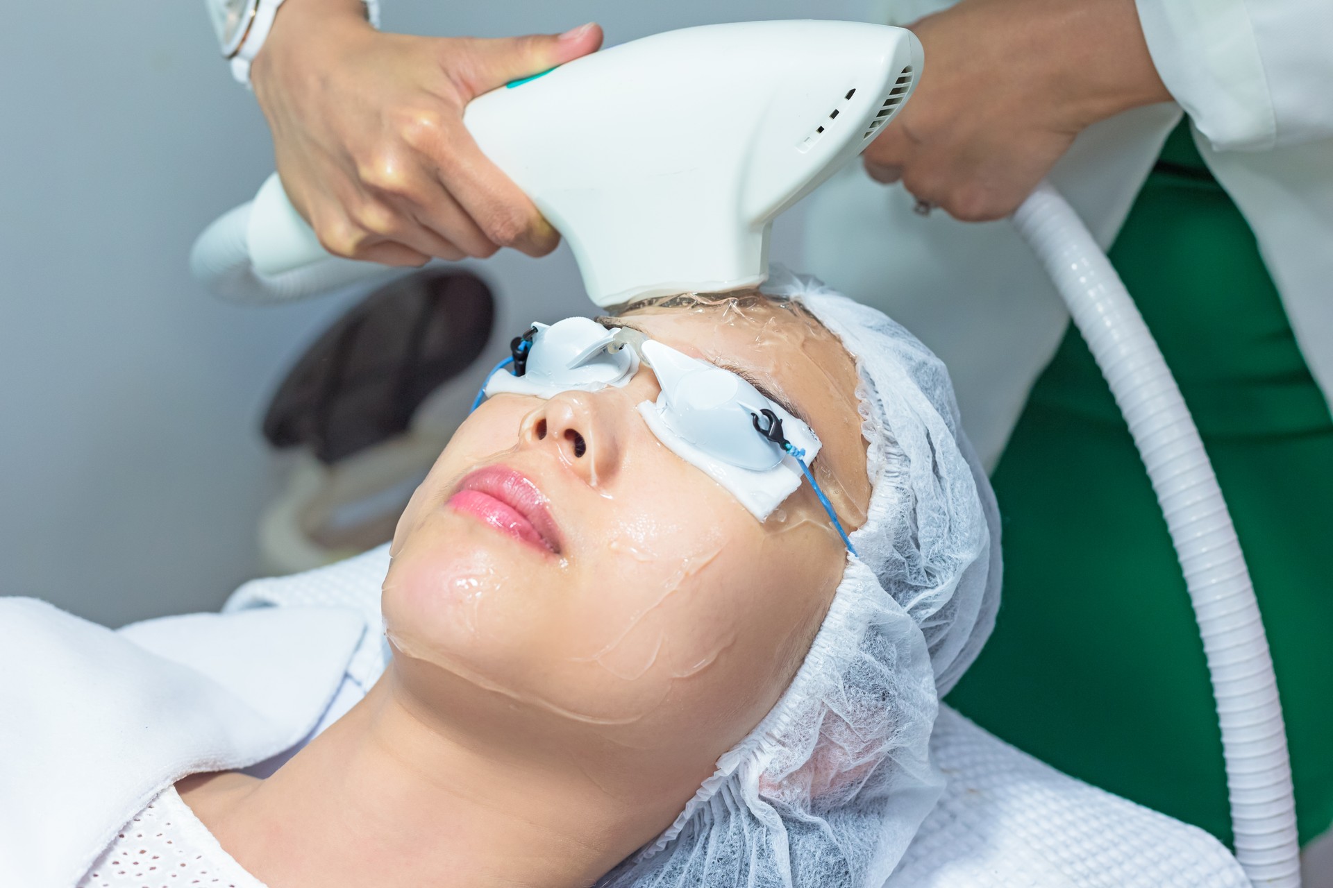 Midsection Of Beautician Applying Cream On Young Woman Face In Spa